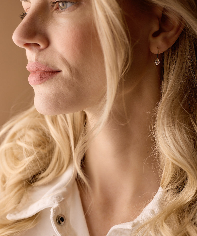 Model Wearing Golden Titanium Bicone Pendant 14mm Ear Rings in Clear Crystal