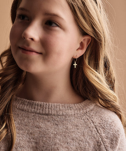 Golden Titanium Cross Pendant earrings on child model. 